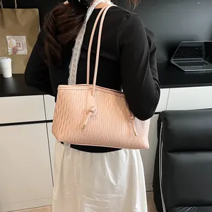 Detail of light pink shoulder bag featuring elegant pleated texture and knotted straps