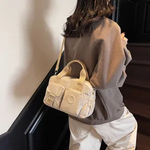 Detail of beige nylon crossbody bag with multi-pocket design and adjustable strap