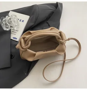 Close-up of ruched beige cloud bag with magnetic closure and soft pleated leather detail