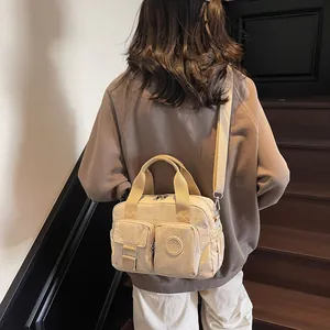 Detail of a beige multi-pocket nylon tote bag with fashion logo and adjustable strap