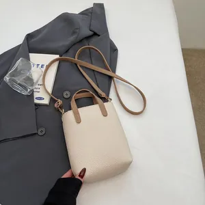 Vue détaillée du sac seau blanc crème texture litchi avec poignées en cuir marron