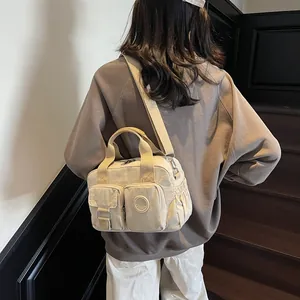 Detail of beige nylon commuter bag featuring functional front pockets and drawstring side