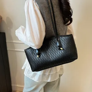 Detail of black wave-patterned leather tote bag with elegant golden metal knot accents