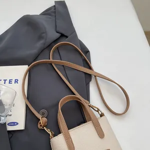 Vue détaillée du mini sac seau en cuir grainé avec poignées contrastées en marron