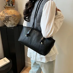 Detailed view of black wavy textured leather tote bag with elegant gold hardware accents