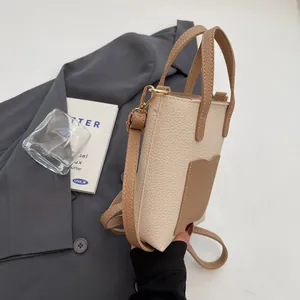 Détail du sac seau bicolore avec texture litchi et finitions métalliques dorées