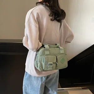 Detail of green nylon bag with multiple pockets and adjustable strap shown on model