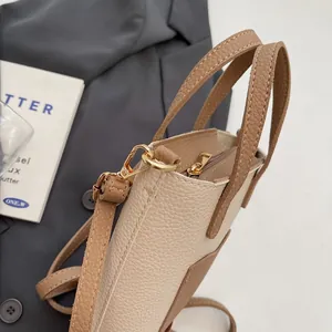 Gros plan du sac seau bicolore montrant la texture du cuir litchi et les détails dorés