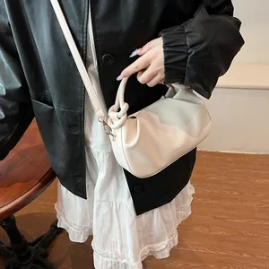 Detail showing creamy white pleated handbag with fashion engraving and knot handle