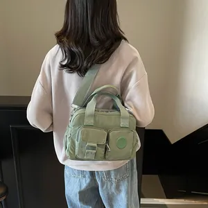 Rear view of model wearing avocado green nylon shoulder bag with multiple pockets