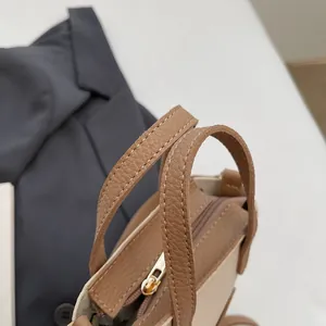 Détail d'un sac seau beige montrant les poignées marron et la fermeture éclair dorée