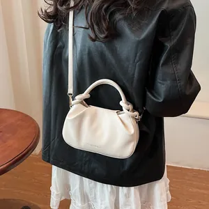 Detail of creamy white pleated cloud bag with adjustable strap and golden hardware