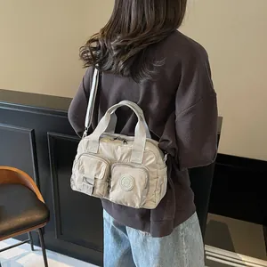 Detail of light grey nylon commuter bag with multi-pocket design and adjustable strap