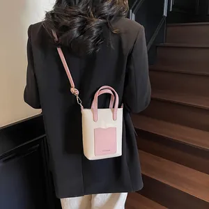 Gros plan d'un sac seau rose et crème avec texture cuir grainé et bandoulière amovible