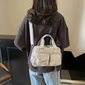 Detail of light grey nylon commuter bag showing multiple zip pockets and adjustable strap
