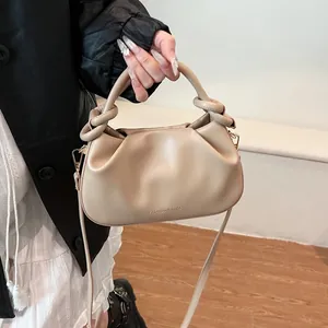 Detail of beige pleated cloud bag with knotted handles and detachable shoulder strap