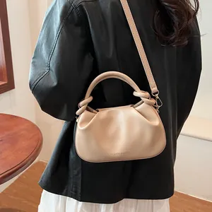 Detail of cream pleated cloud bag with round handles and Fashion & Bags gold lettering