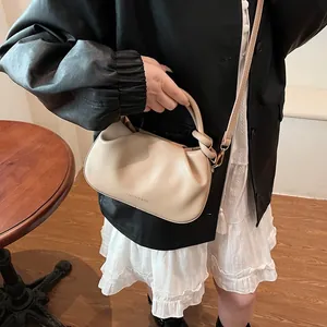 Detail of beige gathered cloud bag with embossed fashion text and slim shoulder strap