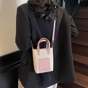 Détail d'un mini sac seau crème et rose avec bandoulière porté par un mannequin