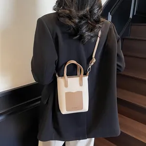 Détail du sac seau minimaliste montrant la texture du cuir et le logo de mode