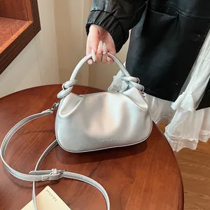 Close-up of silver pleated handbag featuring a knotted handle and metal logo print