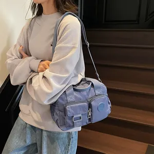 Detail of multi-pocket nylon shoulder bag with adjustable strap and front zippers