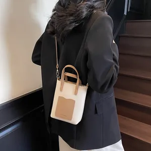 Détail d'un sac seau bicolore minimaliste avec bandoulière réglable et poche pour cartes