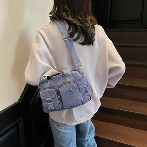 Detail of blue-purple waterproof nylon crossbody bag with functional multi-pockets and logo