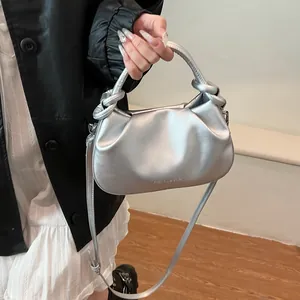Detail of silver pleated cloud bag with embossed lettering and woven top handle