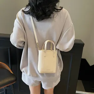 Vue arrière du modèle portant un mini sac seau beige en cuir avec inscription FASHION