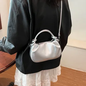 Close-up of metallic silver pleated handbag with fashion lettering and rigid top handle