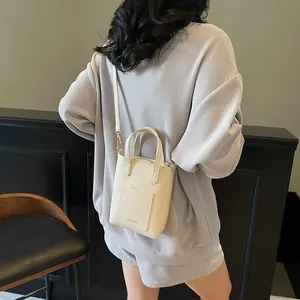 Détail du sac seau en cuir grainé crème montrant la bandoulière et la texture du cuir