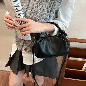 Detail of black pleated cloud bag with knotted handle and adjustable strap in street style