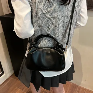 Detail of black pleated faux leather crossbody bag with Fashion & Bags engraving on front