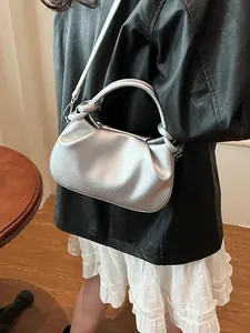 Silver pleated crescent handbag with adjustable strap shown with casual fashion outfit