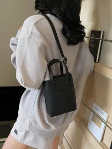 Sac seau minimaliste en cuir noir avec poignées supérieures et bandoulière réglable