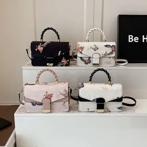 Detailansicht von vier Handtaschen mit Blumen- und Schmetterlingsdruck in Schwarz, Rosa