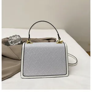 Dettaglio della borsa squadrata in pelle blu chiaro con finiture dorate e bordi bianchi