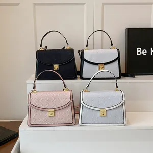 Dettaglio di quattro borse a tracolla in nero, beige, rosa e blu con chiusure dorate in metallo