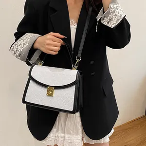 Dettaglio borsa bianca a trama intrecciata con bordo nero e fibbia dorata su modella