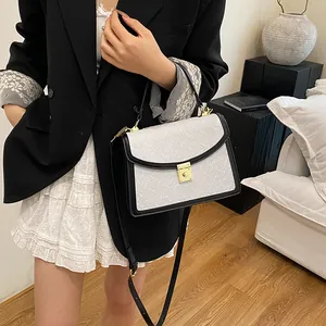 Dettaglio della borsa bianca goffrata con bordo nero e chiusura in metallo dorato