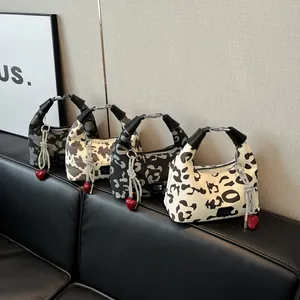 Detail view of four stylish animal print hobo bags with heart charms on a leather bench