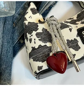 Detail of cow print handbag with sparkling rhinestone tassel and red heart charm