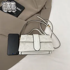 Detailed close-up of white crossbody bag featuring exquisite butterfly embroidery and flap closure