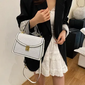 Borsa a tracolla bianca strutturata con fibbia dorata indossata da modella in interni