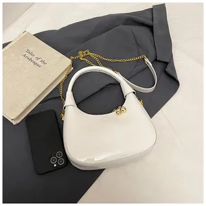 Detail of white glossy crescent bag featuring gold chain strap and metallic ball charms