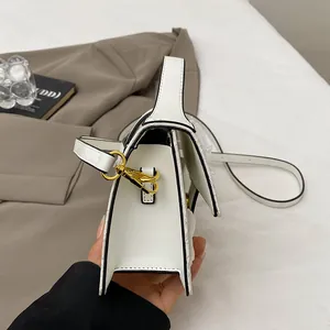 Detail of white square bag with black oil edges, accordion sides, and gold hardware