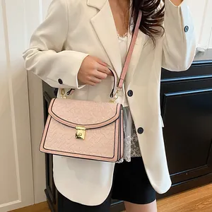 Dettaglio borsa quadrata rosa goffrata con fibbia oro su modella in blazer