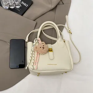 Détail du sac seau crème texture litchi avec fermoir doré et breloque ourson