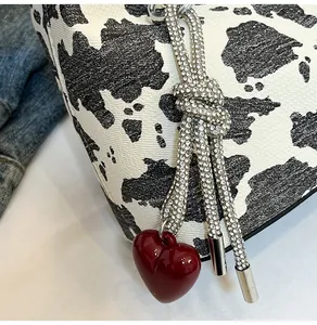 Close-up of cow print bag featuring rhinestone rope and a deep red heart pendant